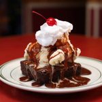 Brownie topped with ice cream, chocolate sauce, whipped cream and a cherry